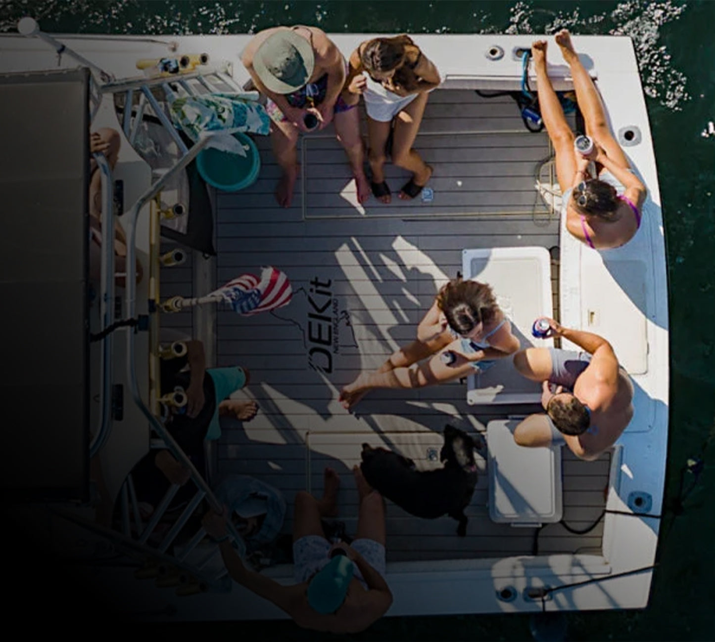 Photo of a American family enjoying a boat out on the water depicting a DEKit logo in the center. The boat has anchor gray over black foam boat flooring with faux teak lines.